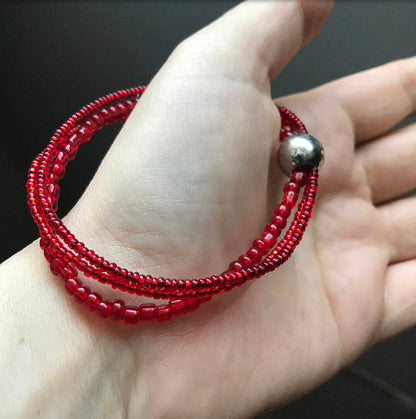 BLOOD RED BEAD BRACELET HANGING FROM THE THUMB