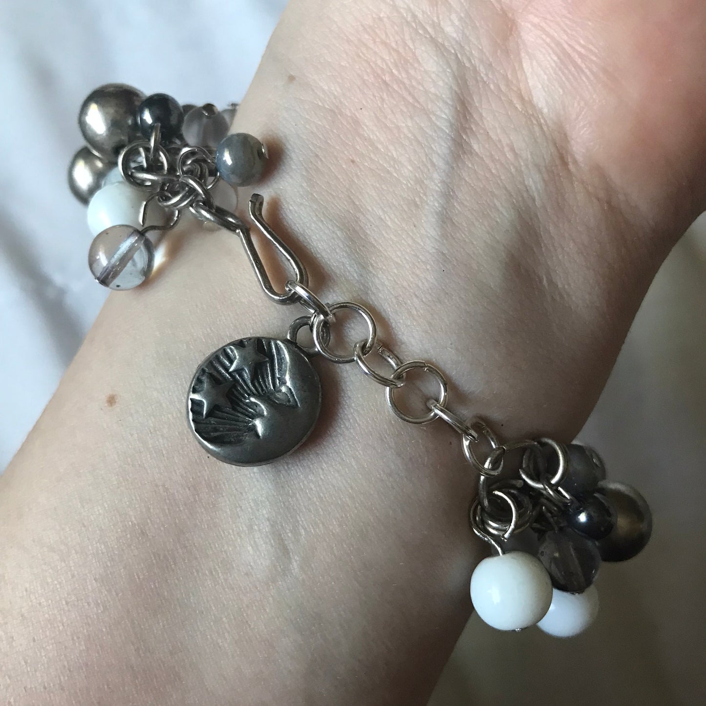 CELESTIAL CHARM BRACELET ON THE WRIST SHOWING THE CLASP  WITH THE MOON & STAR SIDE OF THE EXTENSION CHARM