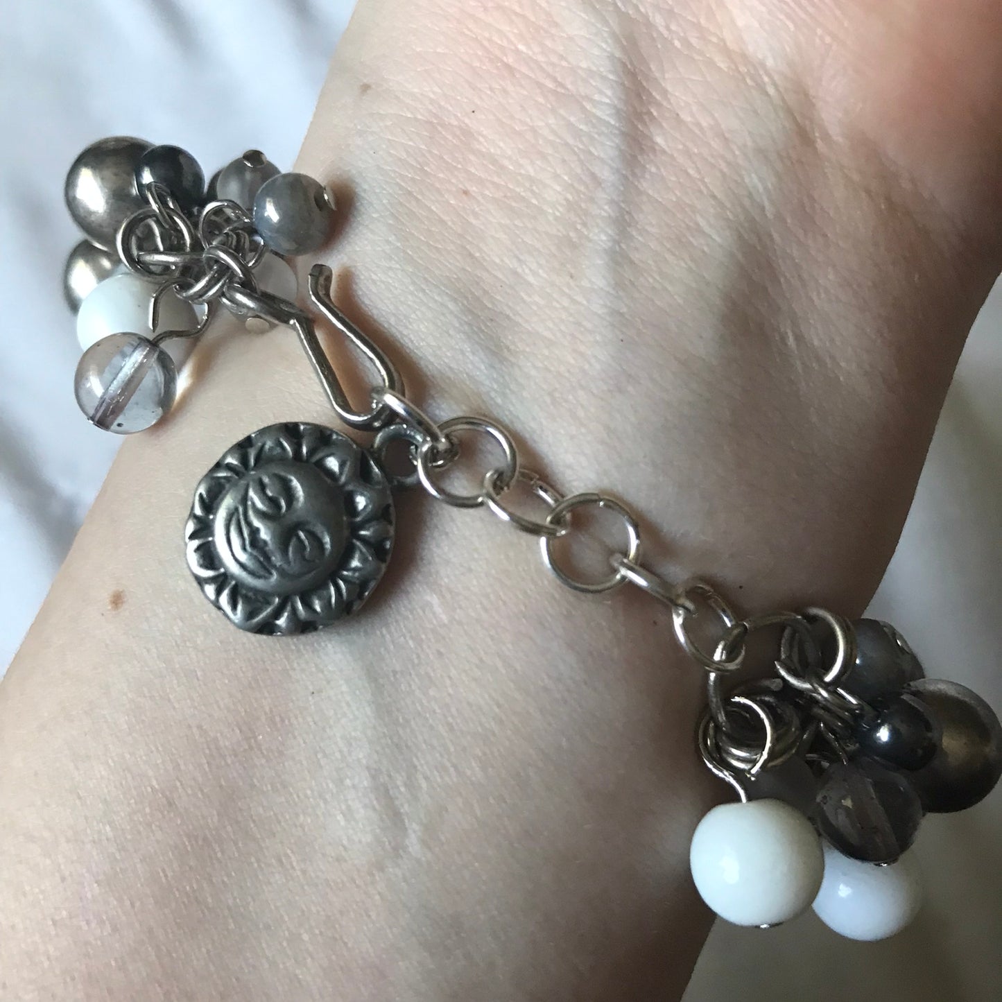 CELESTIAL CHARM BRACELET ON THE WRIST SHOWING THE CLASP  WITH THE SUN SIDE OF THE EXTENSION CHARM